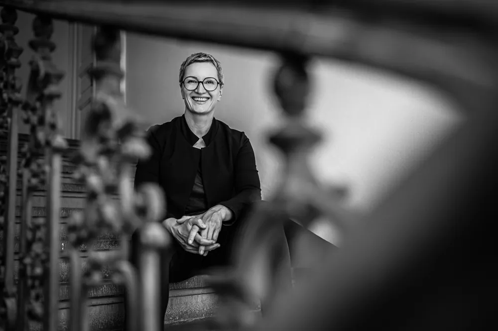 Daniela Krainčić sitzt lachend auf einer Treppe hinter einem Geländer